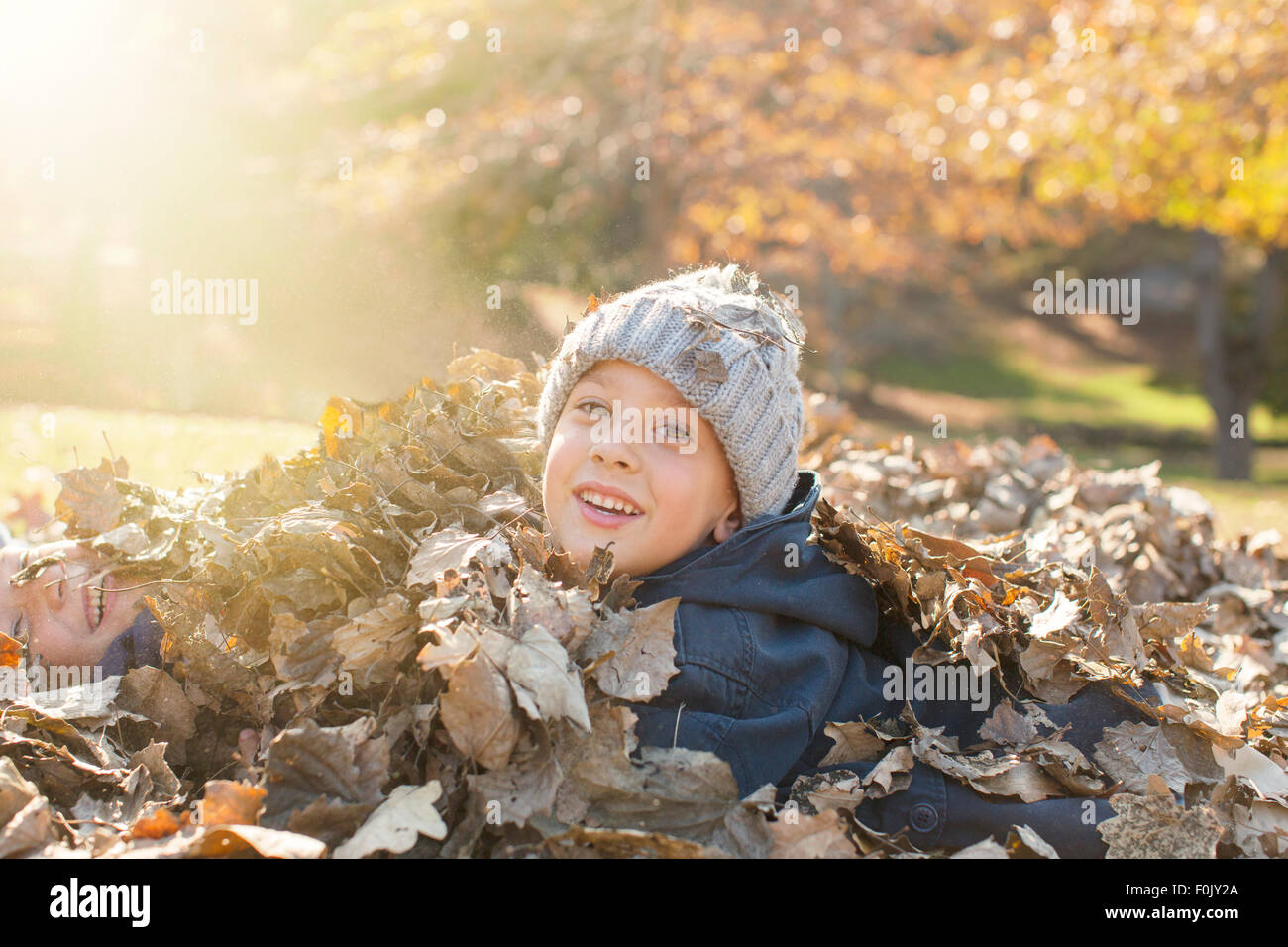 Portrait smiling boys couvert de feuilles d'automne Banque D'Images