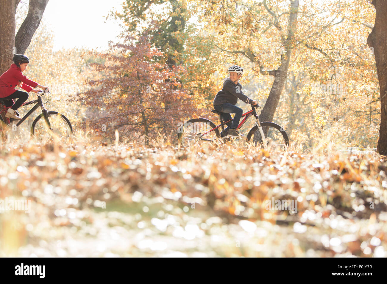 Garçon et fille du vélo dans les bois avec les feuilles d'automne Banque D'Images