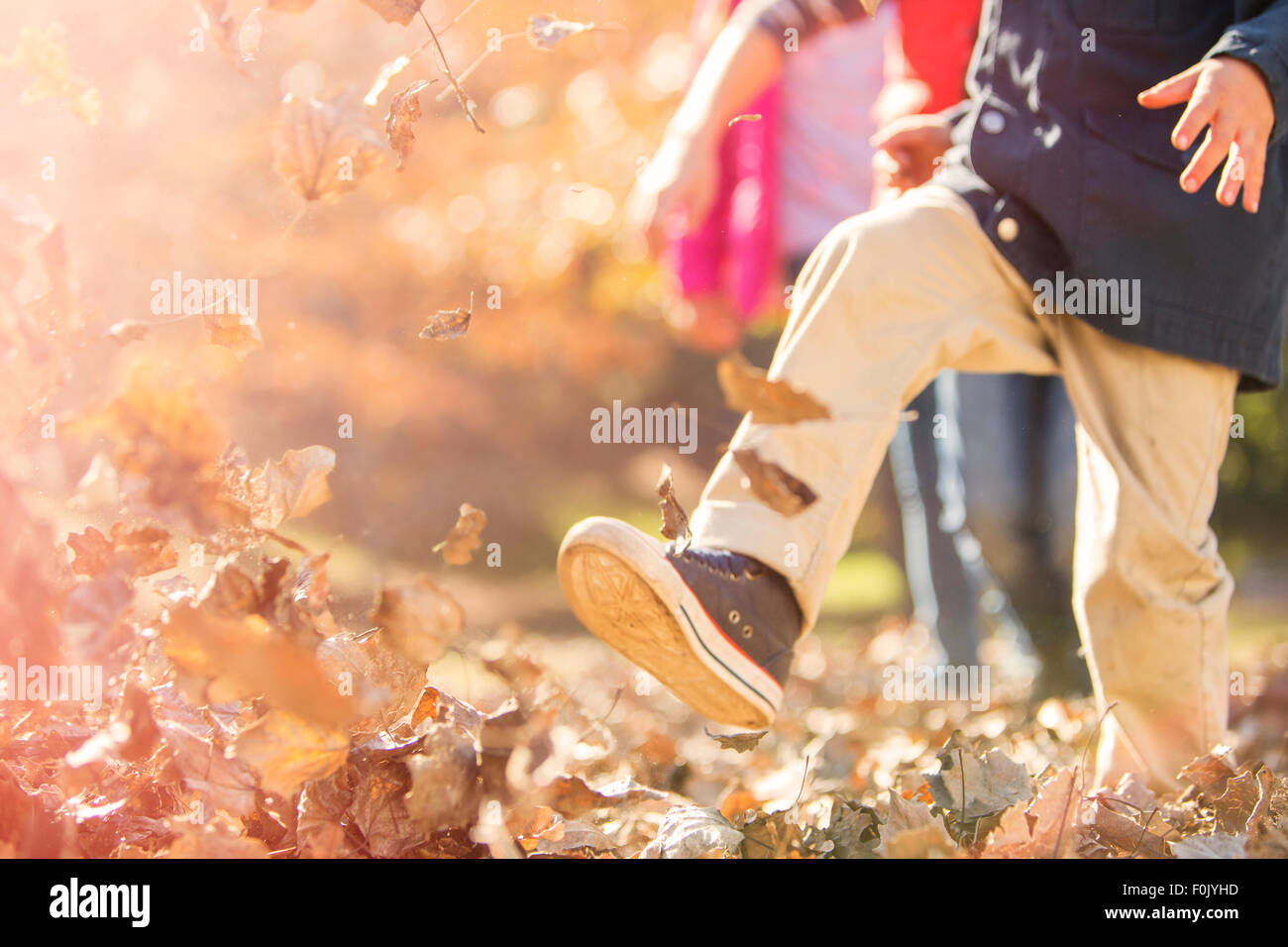 Garçon courir et sauter dans les feuilles d'automne Banque D'Images