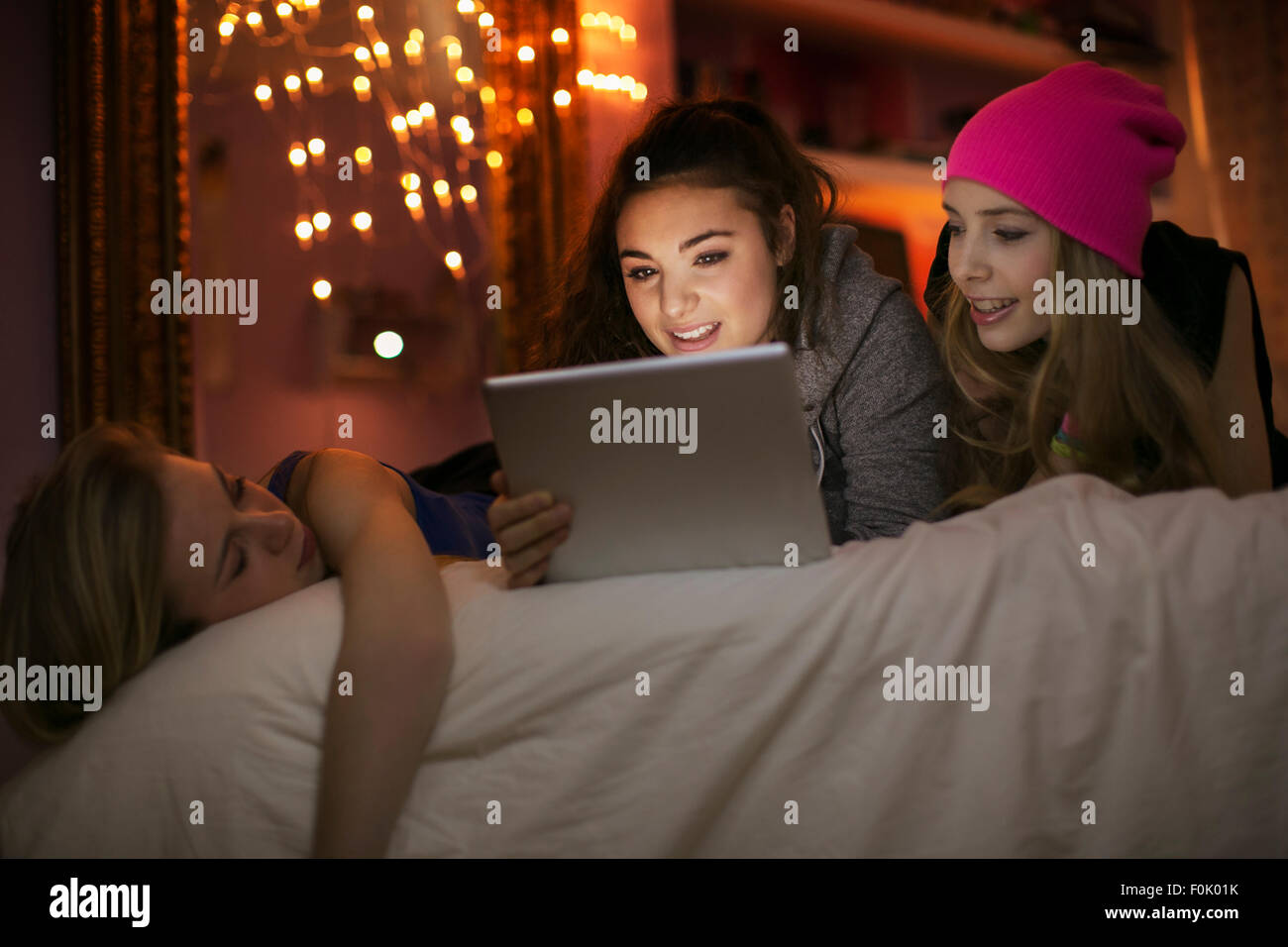 Teenage Girls using digital tablet on bed Banque D'Images