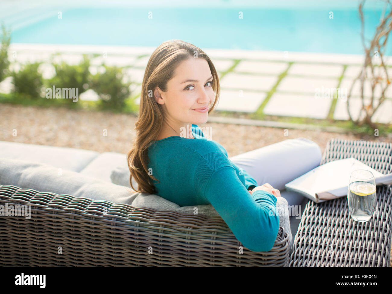 Portrait of smiling woman reading magazine à la piscine de luxe Banque D'Images