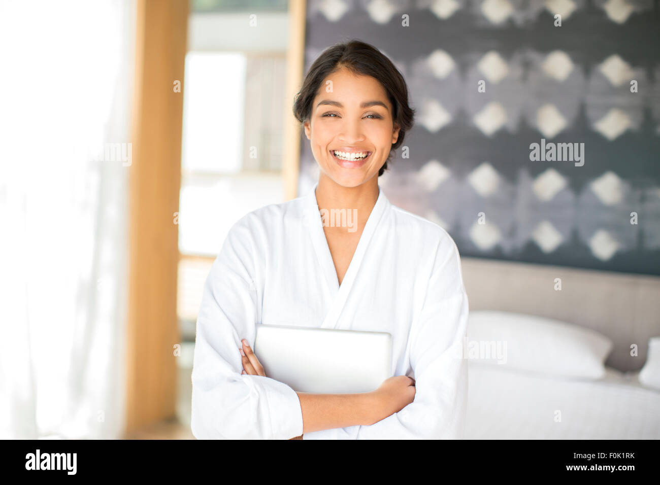 Portrait of smiling woman in bathrobe holding digital tablet Banque D'Images