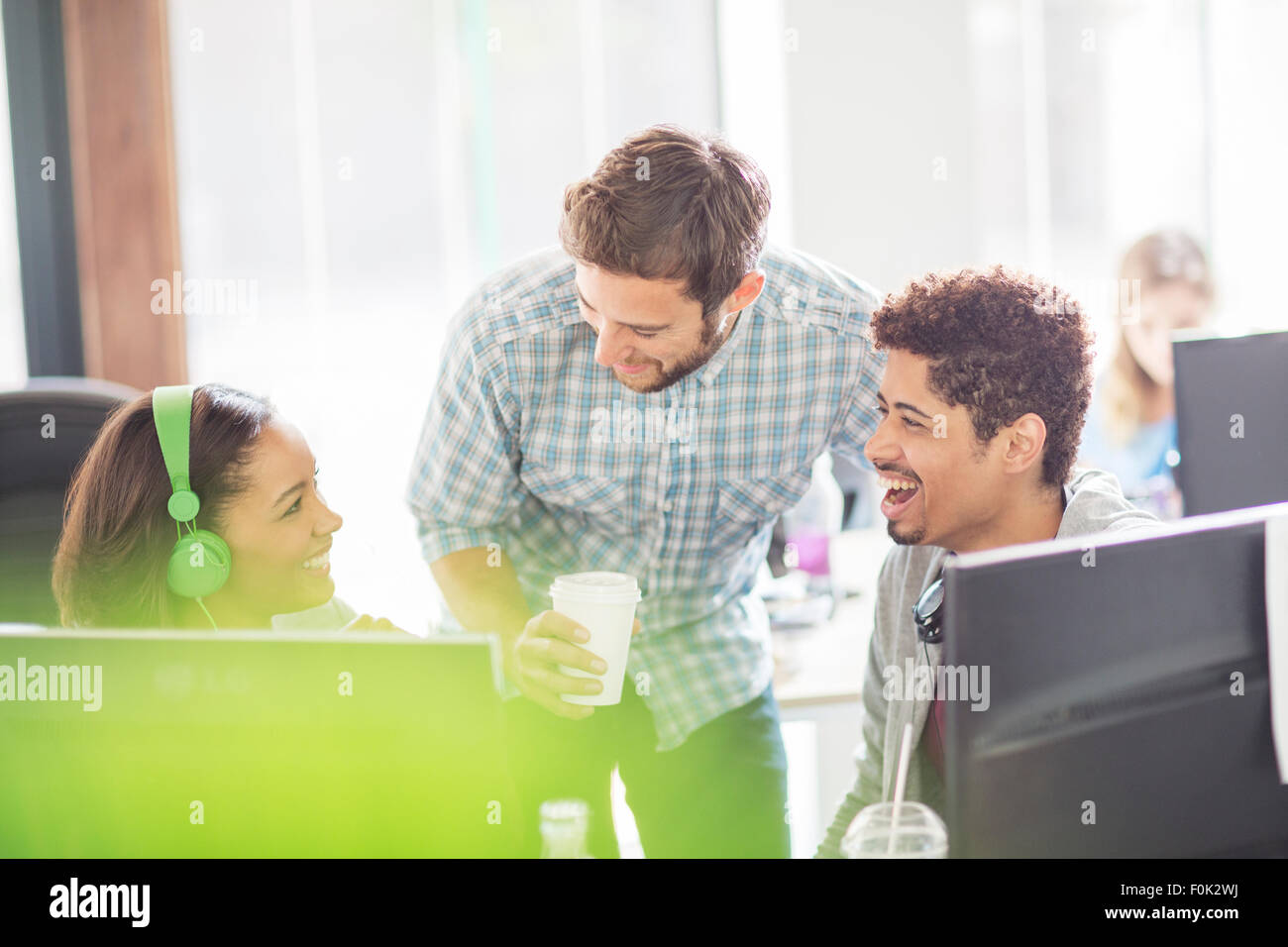 Les gens d'affaires créatifs avec des écouteurs et du café de rire de l'informatique Banque D'Images