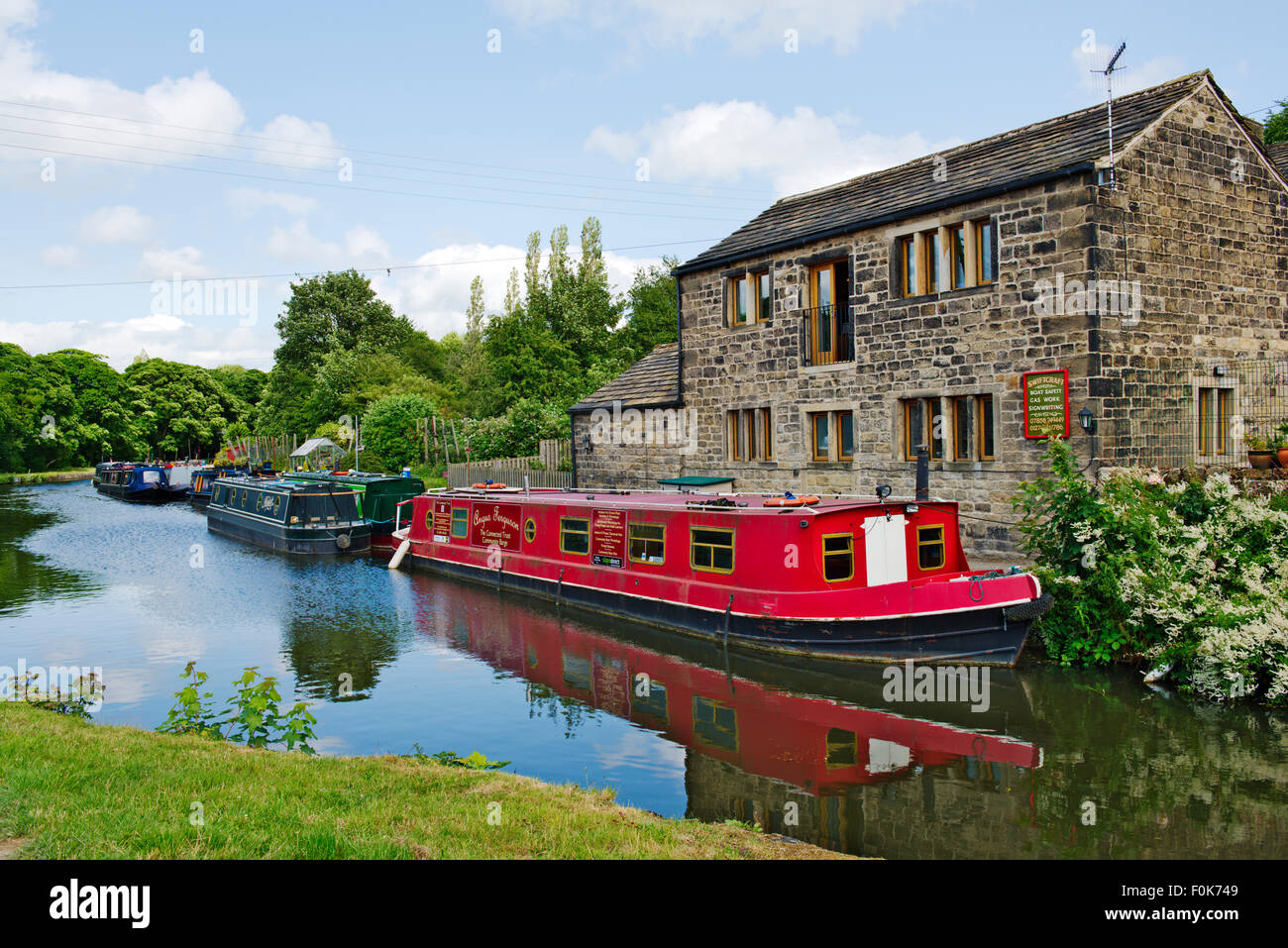 Canal étroit les bateaux avec des reflets dans l'eau, chalet traditionnel en pierre, Leeds et Liverpool Canal, West Yorkshire, Royaume-Uni Banque D'Images