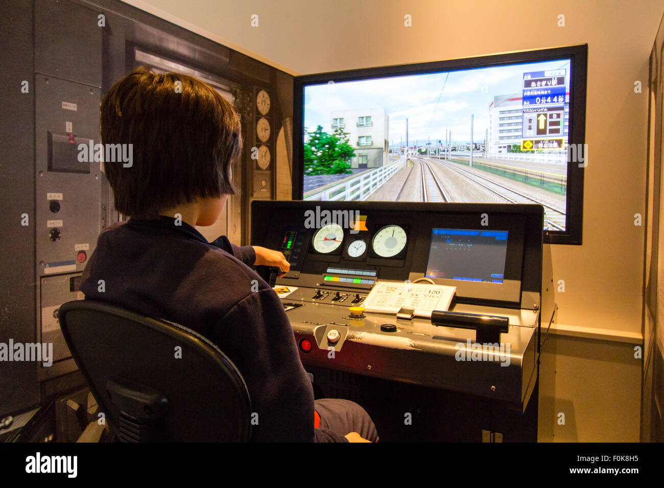 Musée Shinkansen, Nagoya. Plus d'épaule du garçon caucasien enfant, 10 à 12 ans, assis sur le panneau de commande et écran vidéo de train simulator. Banque D'Images