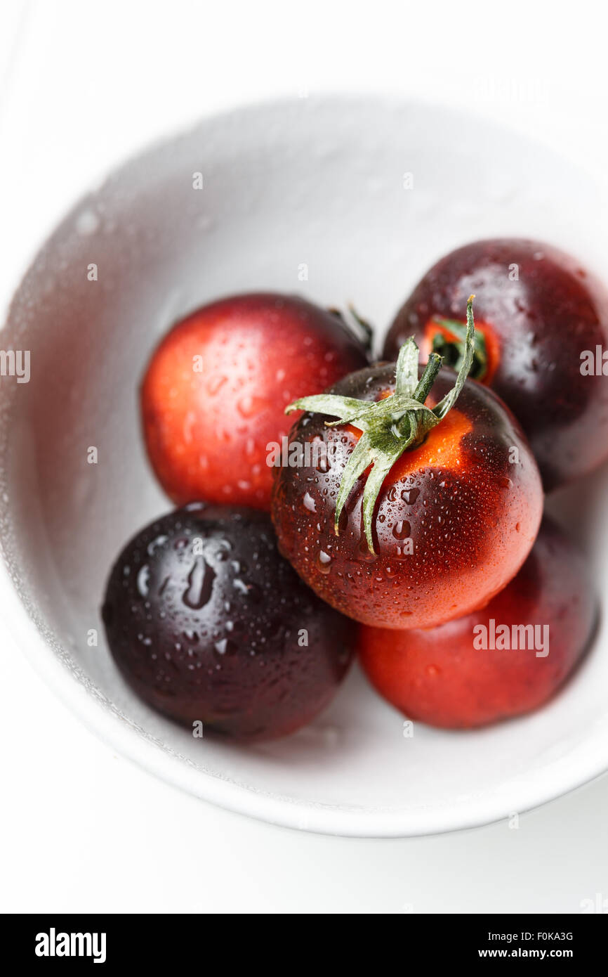 Les tomates noires dans un bol blanc Banque D'Images