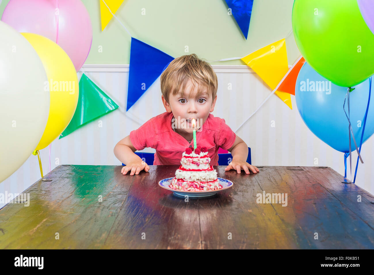 Adorable enfant soufflant la bougie sur son gâteau d'anniversaire Banque D'Images