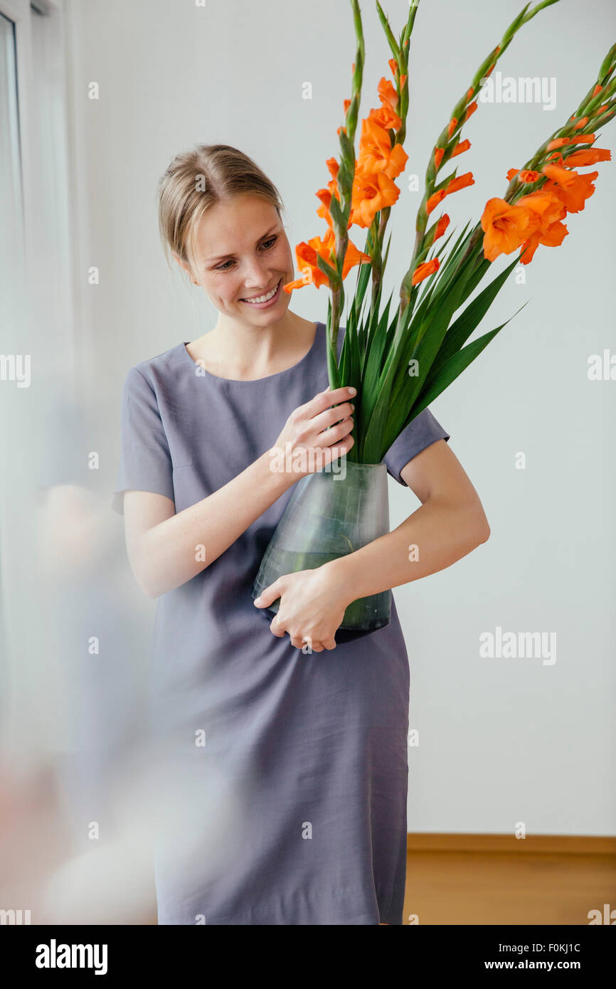 Femme tenant un grand vase avec des glaïeuls Banque D'Images