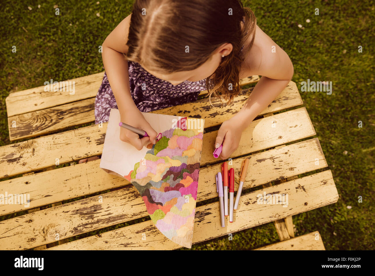 Girl dessin sur un magazine en bois fichier dans jardin Banque D'Images