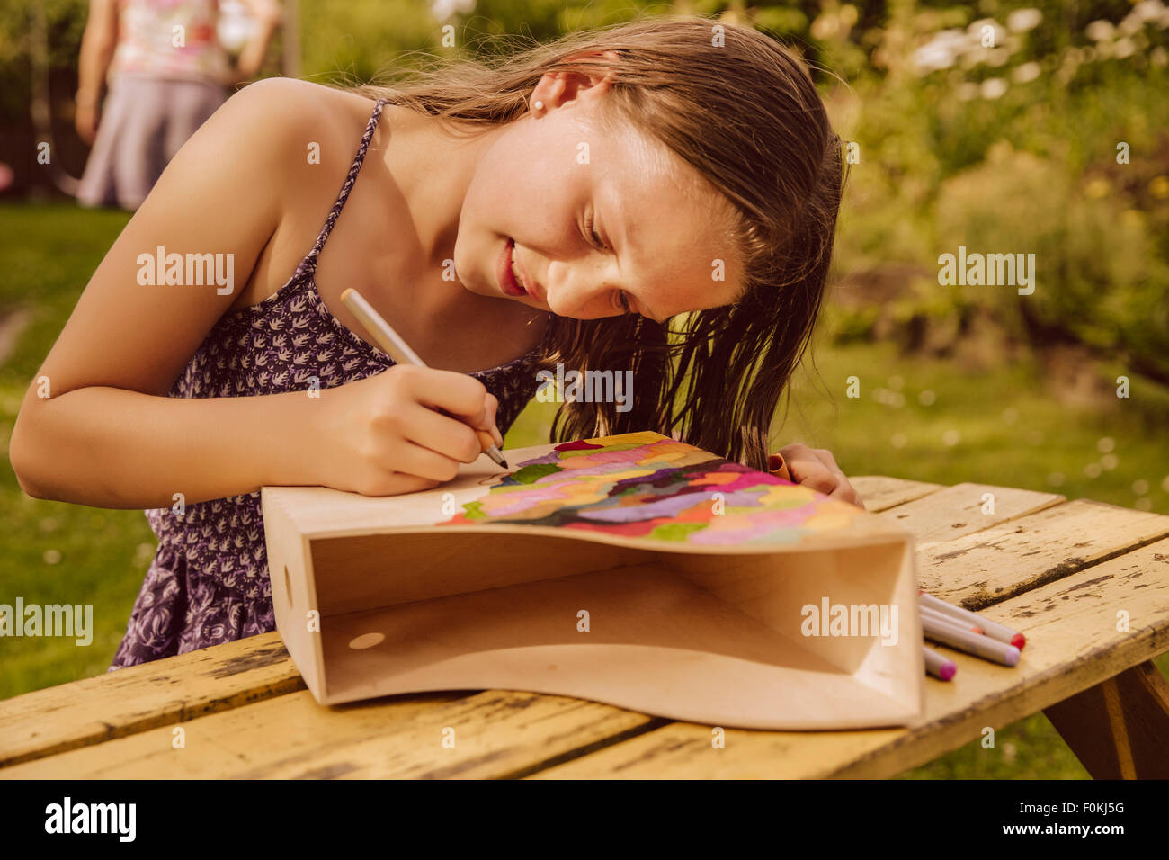 Girl dessin sur un magazine en bois fichier dans jardin Banque D'Images