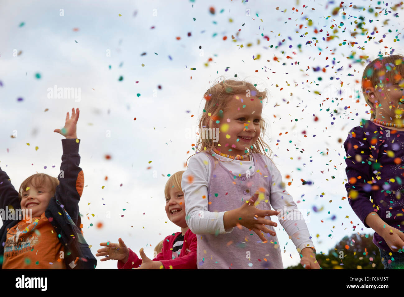 Quatre petits enfants jetant des confettis sur un pré Banque D'Images