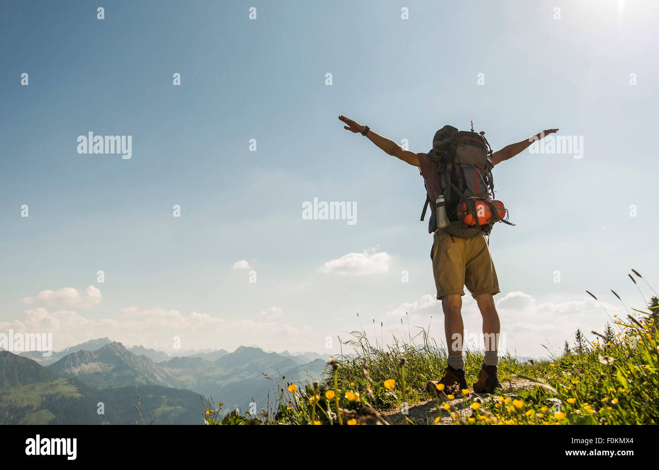 Autriche, Tyrol, Tannheimer Tal, jeune homme debout sur la piste de montagne with arms outstretched Banque D'Images