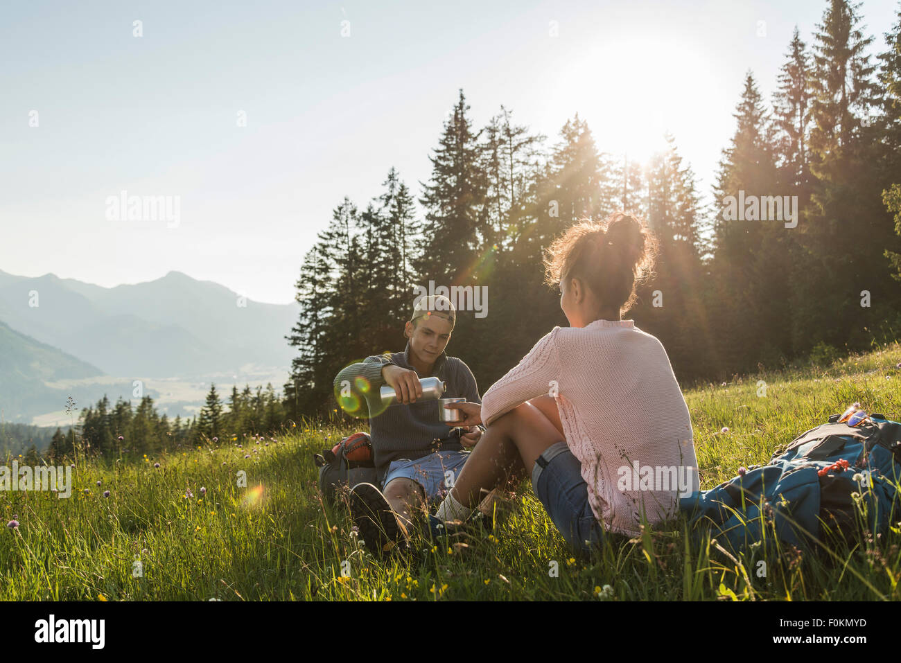 Autriche, Tyrol, Tannheimer Tal, jeune couple reposant sur pré alpin Banque D'Images