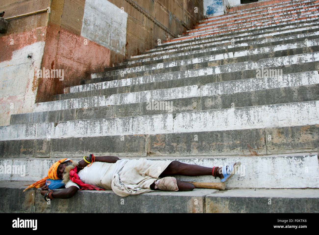 Pattes non identifiés sadhu dormir sur les marches d'un ghat, Inde 20123. La pauvreté augmente en Inde Banque D'Images