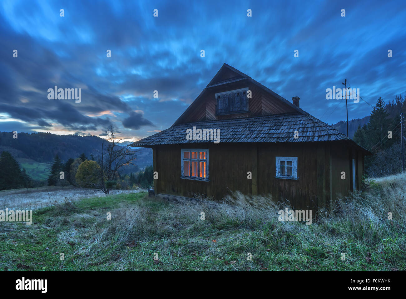 Soirée fantastique rougeoyant paysage par la lumière du soleil. Scène d'automne spectaculaire avec maison en bois. Carpates, l'Ukraine, l'Europe. Banque D'Images