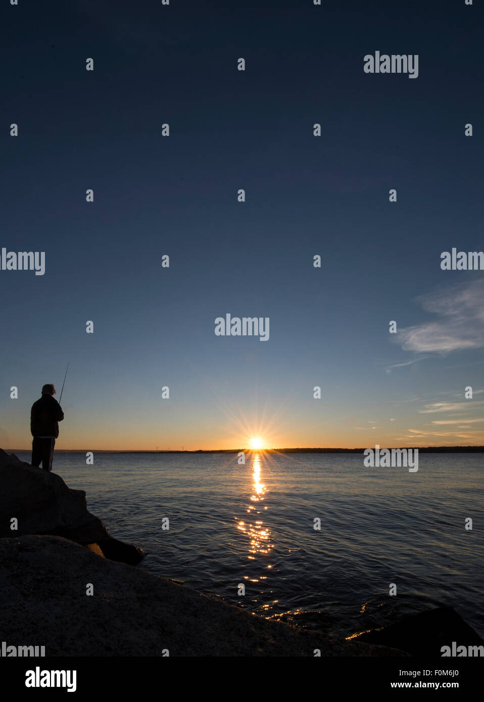 Silhouette d'un jeune pêcheur à la tombée de la pêche Banque D'Images