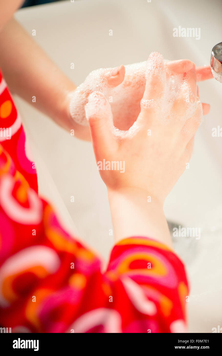Close up of a little girls les mains avec de l'eau savonneuse. Elle se lave les mains dans une salle de bains. Banque D'Images