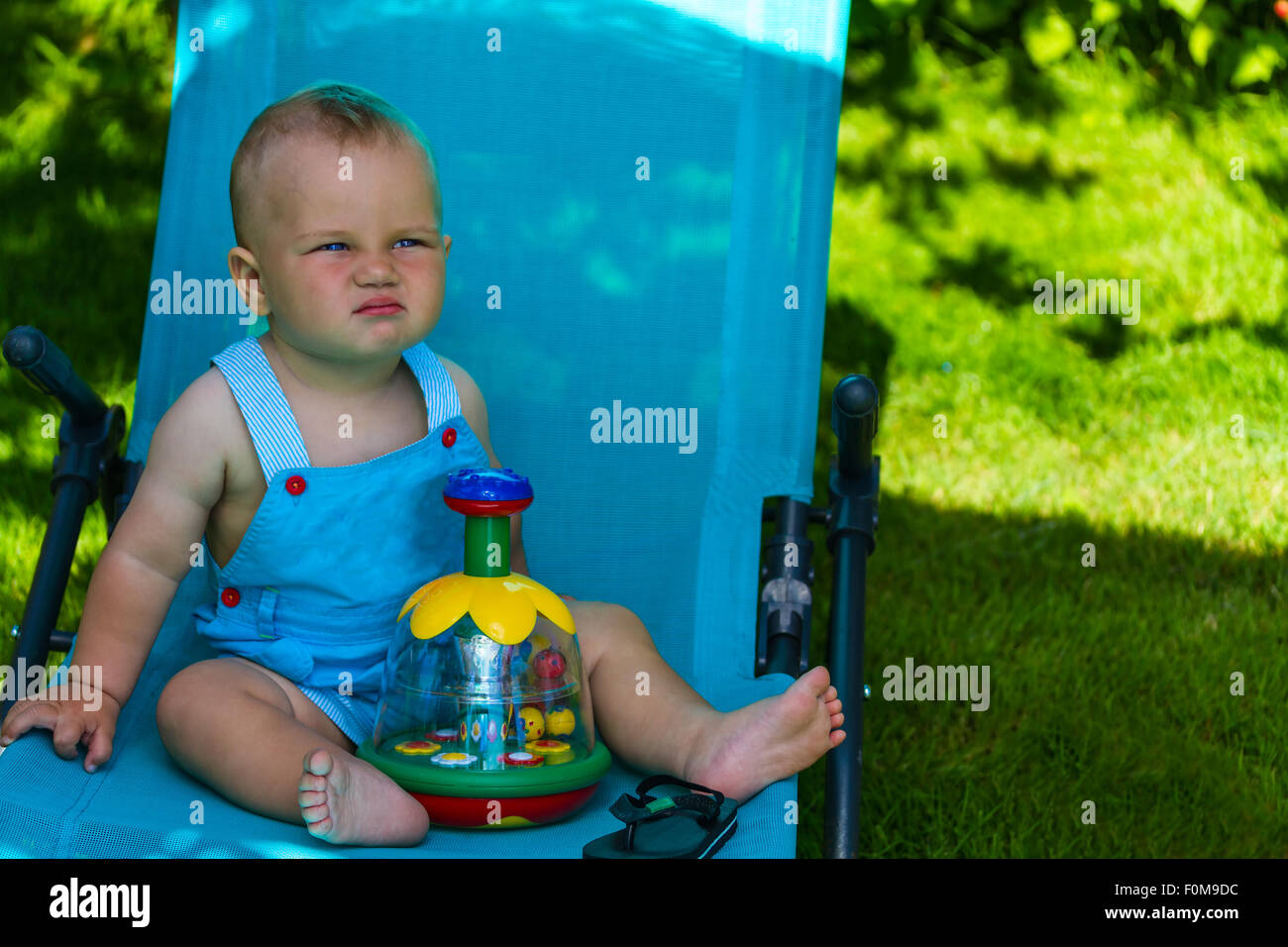Charmant caucasian baby boy sur chaise longue dans park Banque D'Images