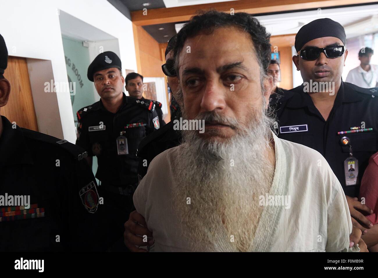 Dhaka, Bangladesh. 18 août, 2015. Le personnel du bataillon d'action rapide du Bangladesh accompagner suspect et le Bangladesh, citoyen britannique d'origine Touhidur Rahman, qui a été arrêté avec deux autres suspects pour le meurtre de deux éminents blogueurs athée, lors d'un photocall des médias à Dhaka le 18 août 2015. D'élite des forces de sécurité du Bangladesh ont arrêté trois militants islamistes présumés, dont un citoyen britannique qui a annoncé la police était la 'main' planificateur de l'assassinat de deux éminents blogueurs athée. Banque D'Images