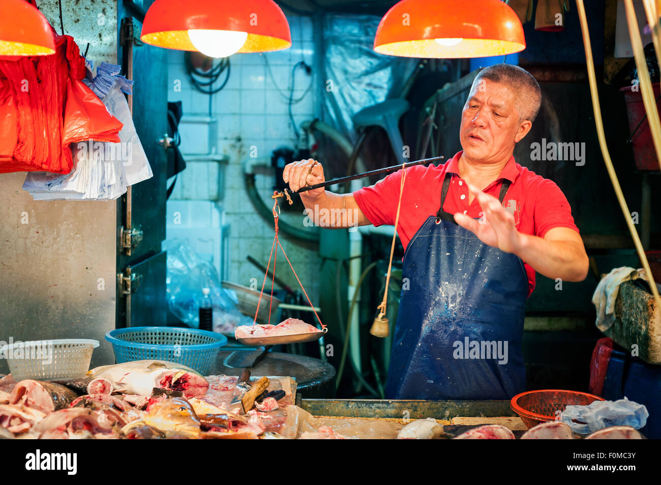 Poissonnier poissons pesant à un marché intérieur de Hong Kong Banque D'Images