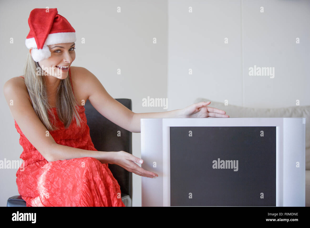 Jeune femme séduisante en robe rouge avec chapeau de Noël Présentation de la radiodiffusion Banque D'Images