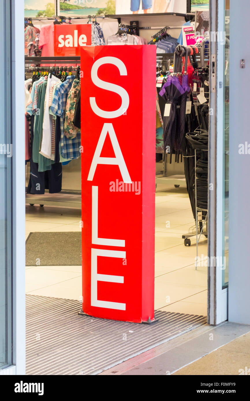 Vente de blanc et rouge vif signe à l'entrée d'un magasin de vêtements au détail Banque D'Images