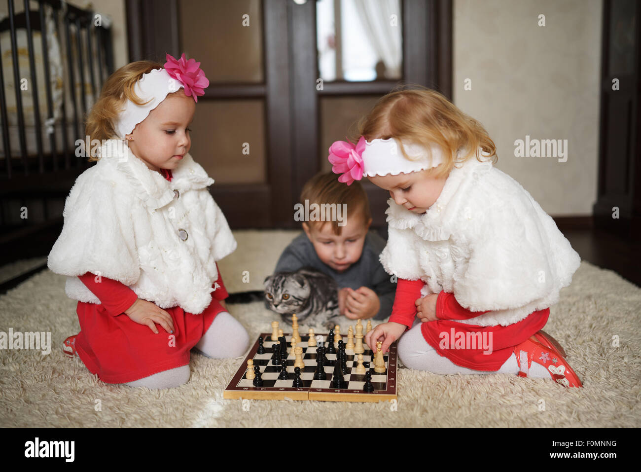 Enfants jouant aux échecs lying on floor Banque D'Images