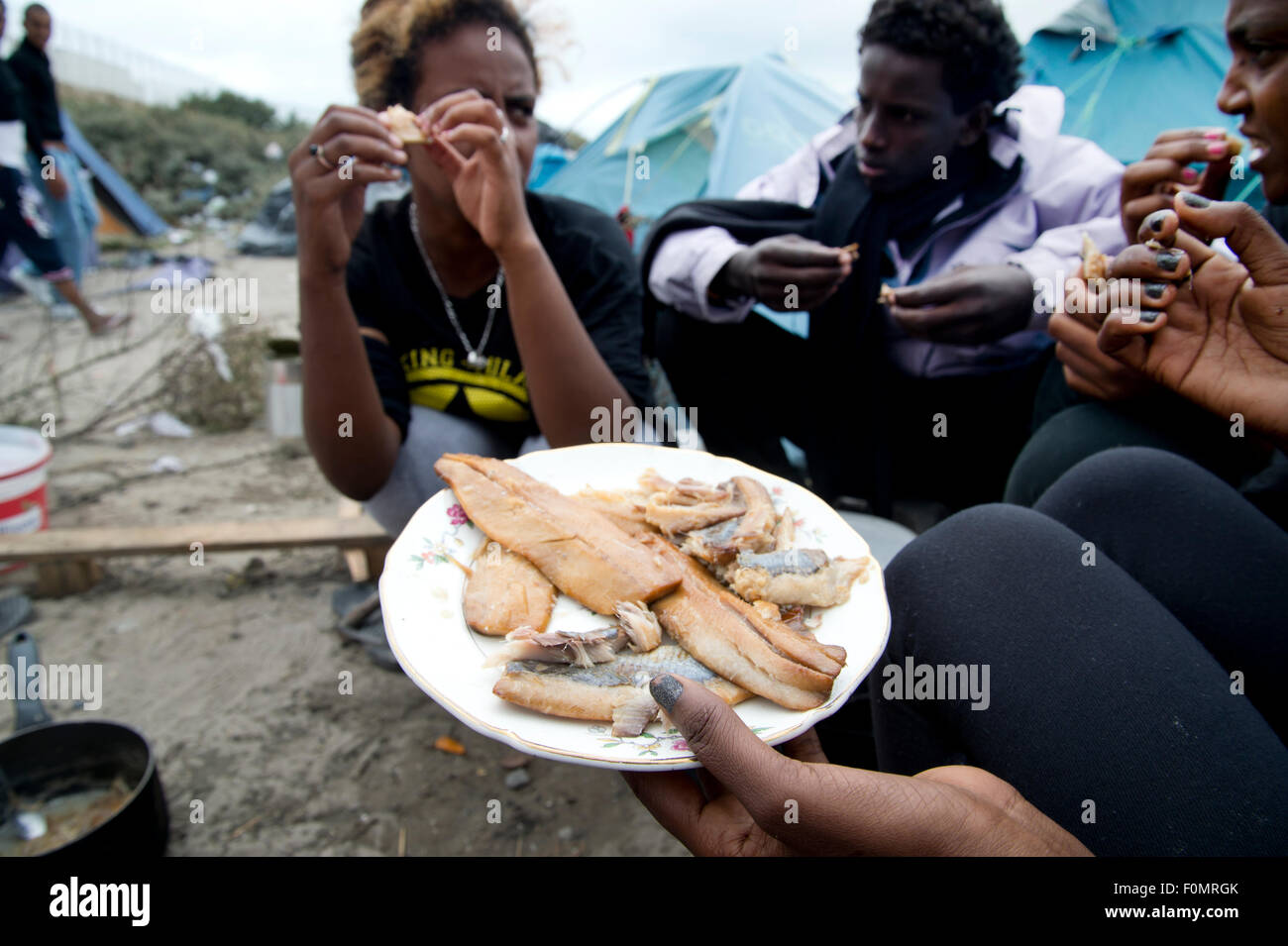 La Jungle, Centre pour les migrants de Calais. Les Érythréens mangent du poisson. Banque D'Images