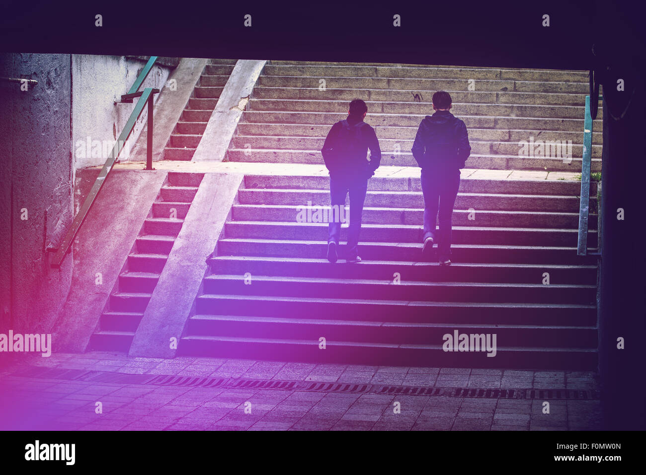 Les gens dans l'environnement urbain, les piétons circulant dans un passage souterrain, les silhouettes des deux femmes escalier en béton d'escalade Banque D'Images