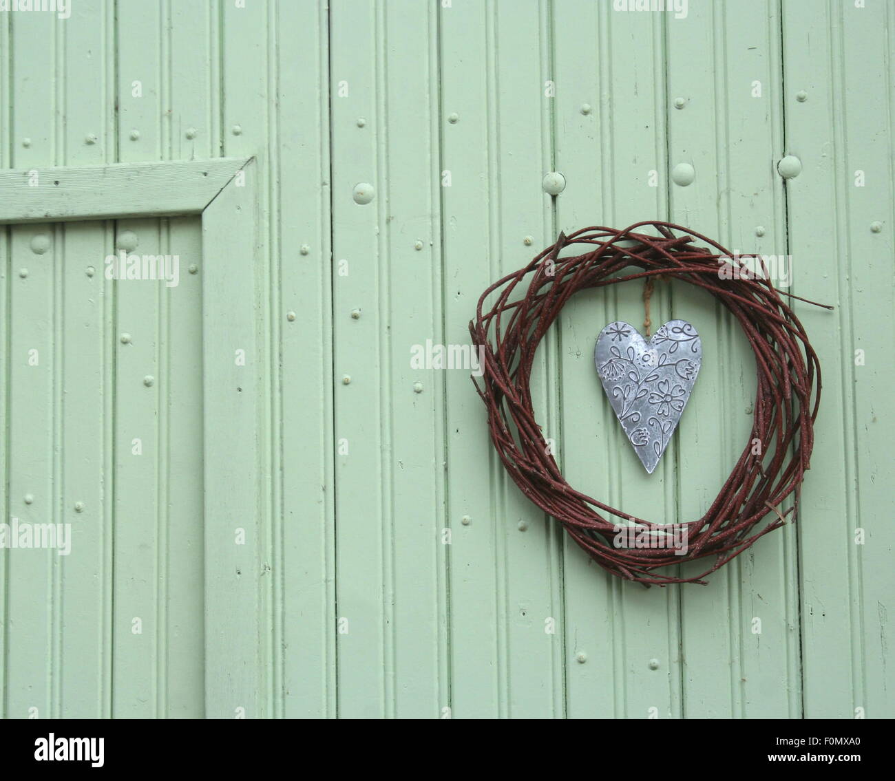 Vintage tin coeur martelé en cercle couronne au mur en bois vert, de l'Allemagne. Banque D'Images