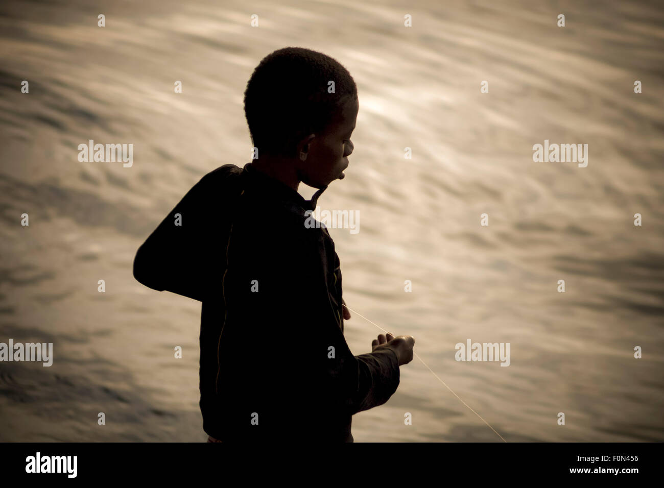 Ombre de jeune enfant à la pêche dans la rivière le Niger avec une seule chaîne. Banque D'Images