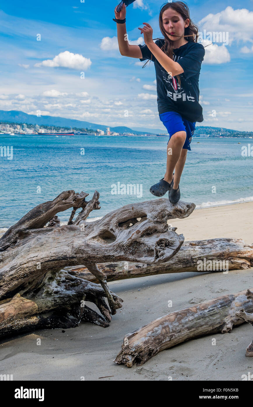 Garçon a fun jumping at Beach dans le parc Stanley, Vancouver, British Columbia, Canada Banque D'Images