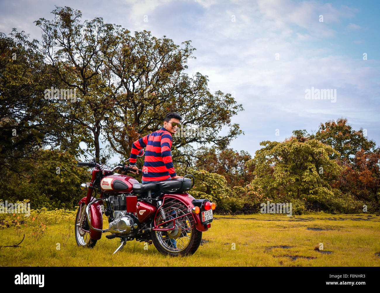 Jeune Indien Garçon posant avec son Royal Enfield Classic 350 vélo en saison d'automne. Banque D'Images