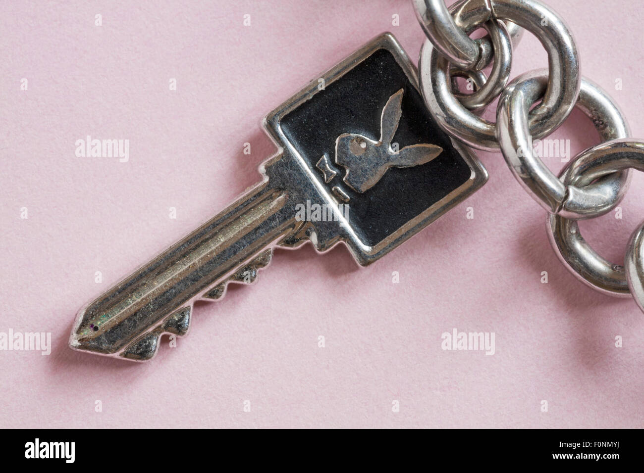 Breloque clé Playboy sur breloque bracelet sur fond rose - logo Playboy lapin Banque D'Images