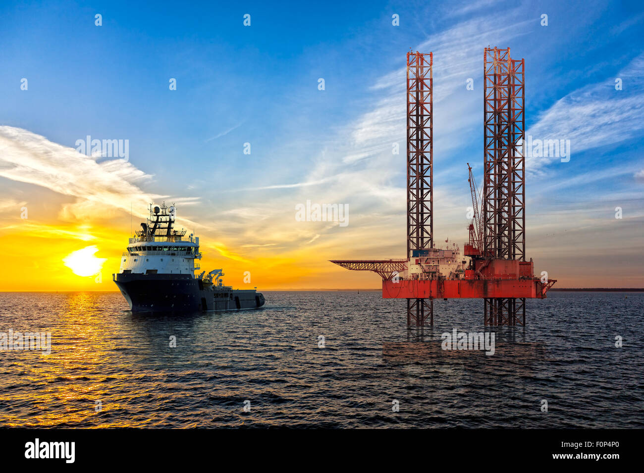 Plate-forme pétrolière et remorqueur sur zone au large des côtes au coucher du soleil. Banque D'Images