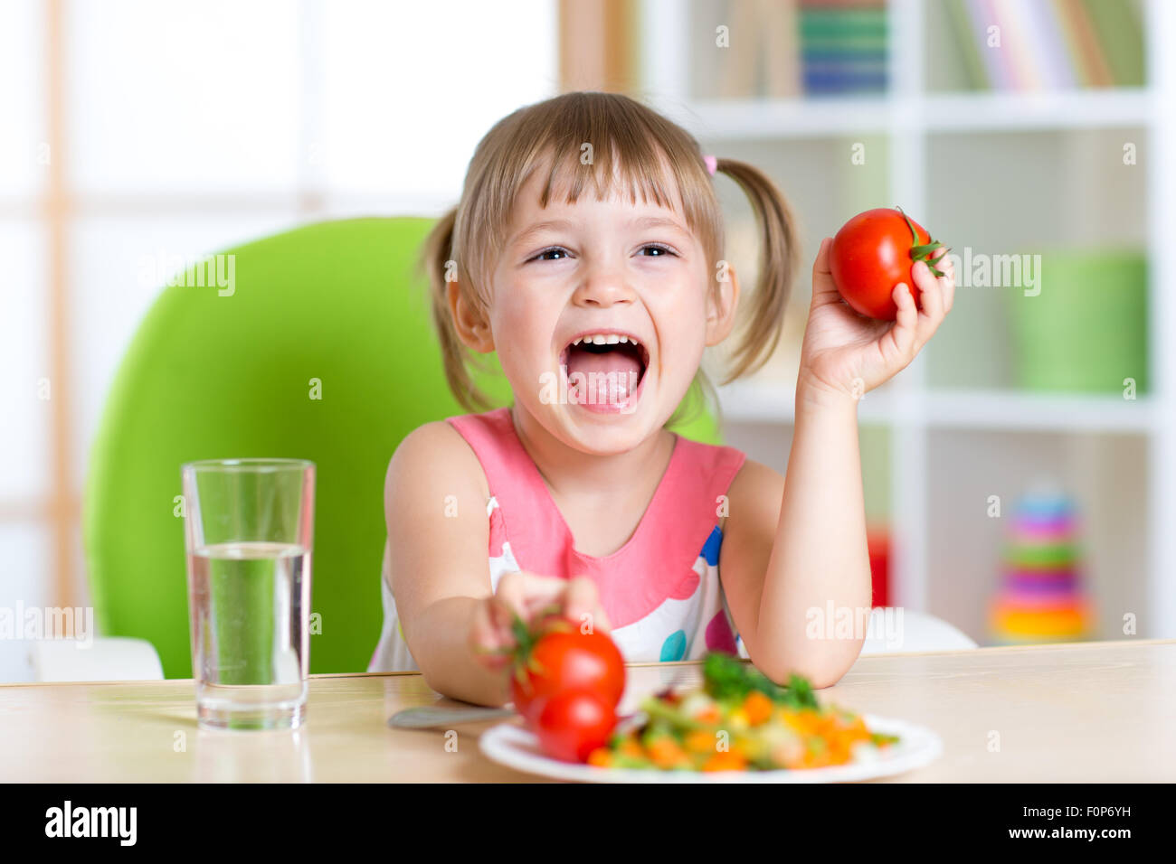 Heureux l'enfant mange le dîner et les spectacles les tomates Banque D'Images