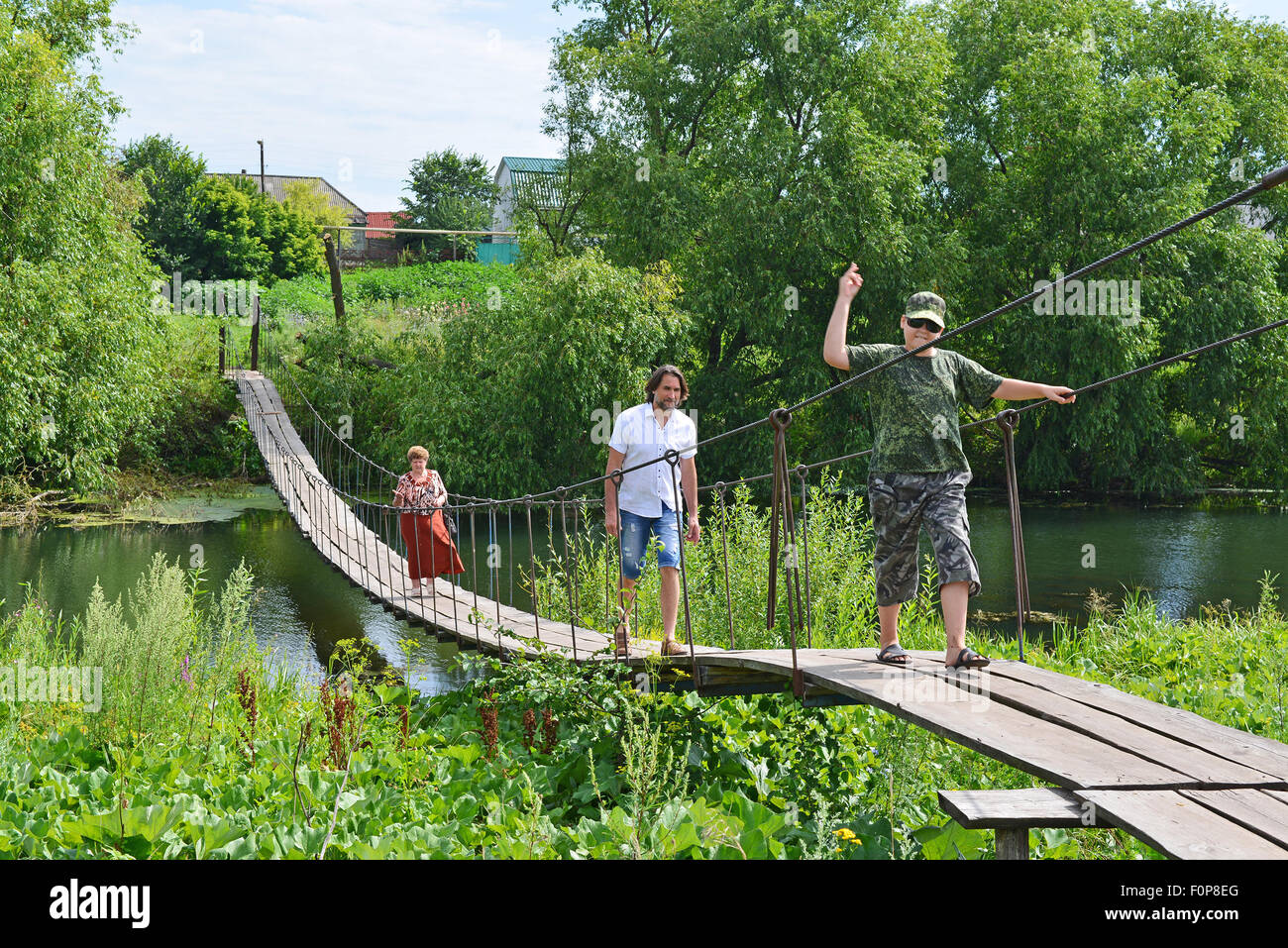 Trois personnes vont sur un pont suspendu au-dessus de la rivière Banque D'Images