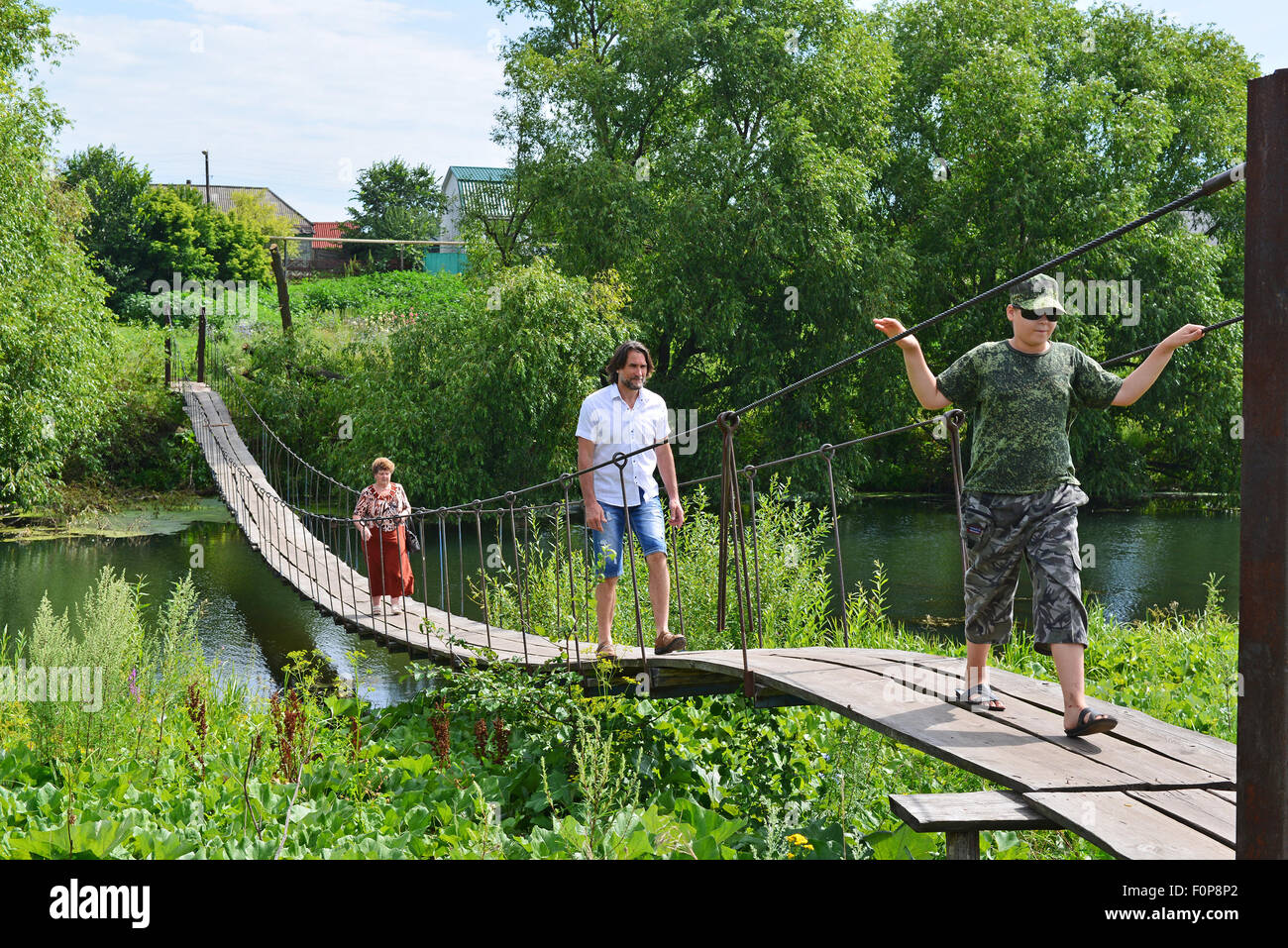 Trois personnes vont sur un pont suspendu au-dessus de la rivière Banque D'Images