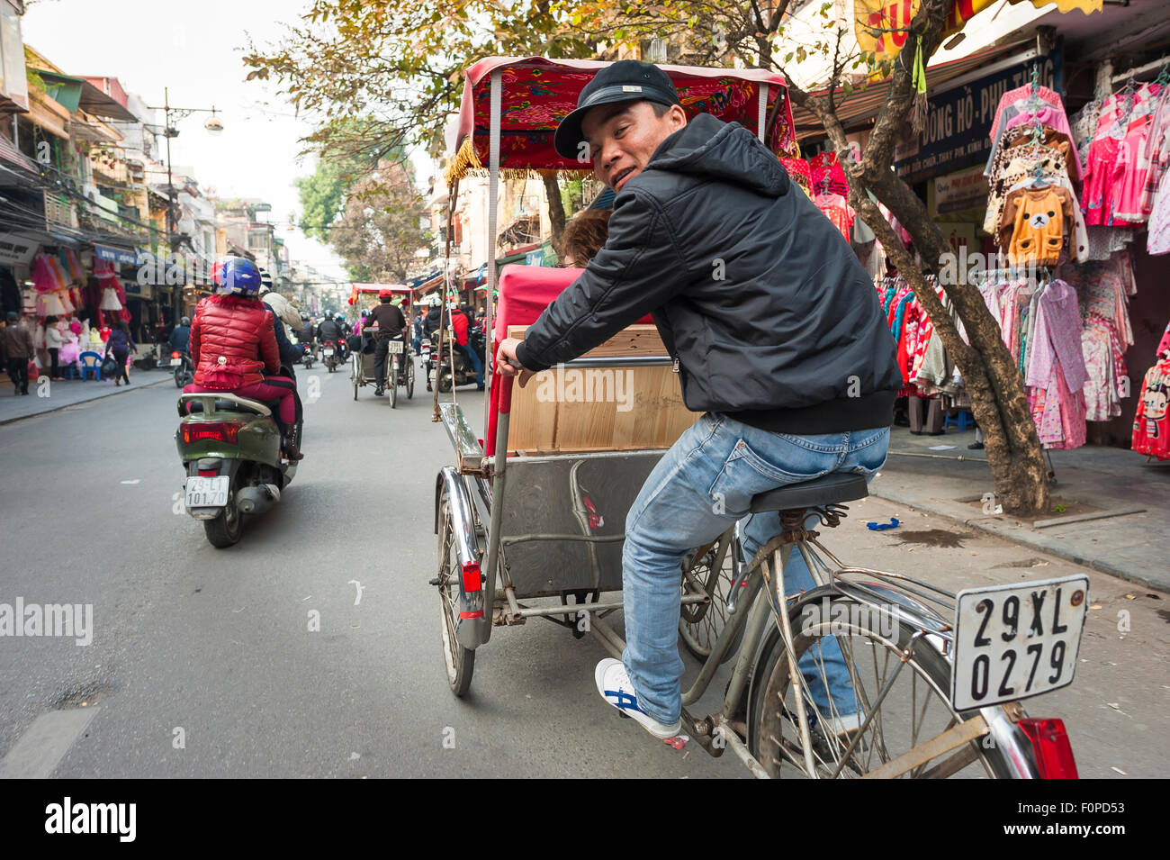 Hanoi pousse-pousse, un conducteur d'un cycle rickshaw à Hanoi d'œil par-dessus son épaule, tout en donnant une visite guidée de la Vieille Ville, Vietnam Banque D'Images