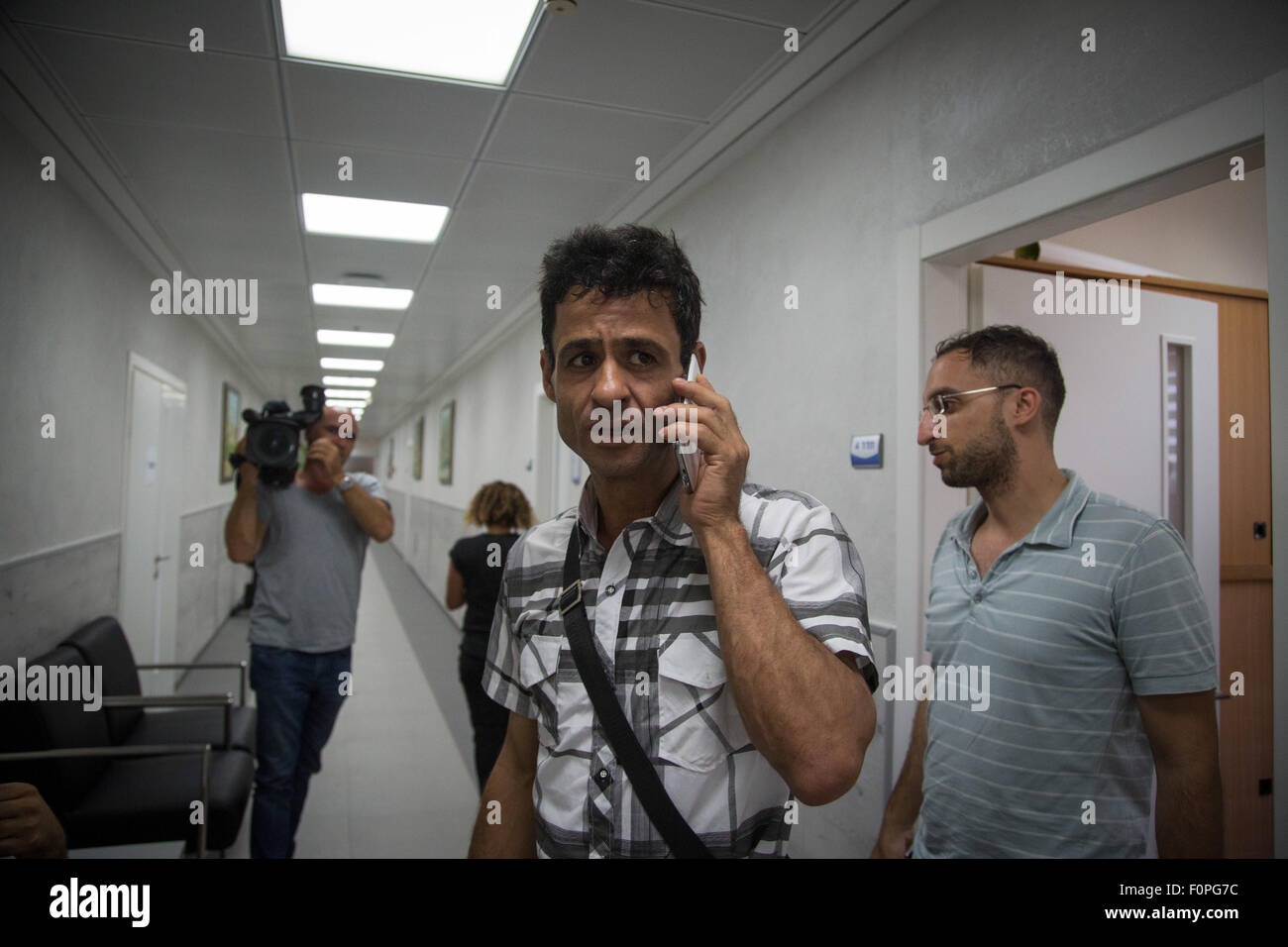 Jérusalem, Israël. Août 19, 2015. Au milieu (C), frère de gréviste de la faim palestinien Mohammad Allan, parle au téléphone à l'hôpital Barzilai à Ashkelon, dans le sud d'Israël, le 19 août, 2015. La haute cour d'Israël a tenu une audition mercredi pour décider de libérer un prisonnier palestinien qui fait la grève de la faim depuis 64 jours. La Cour suprême n'a pas encore pris de décision à savoir s'il accepte une pétition pour libérer Mohammad Allan pour raisons de santé. Allan est protestant contre son emprisonnement sans procès depuis novembre 2014. © Albert/JINI Sadikov/Xinhua/Alamy Live News Banque D'Images