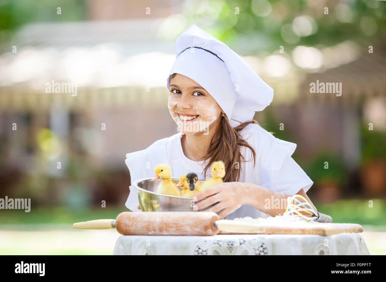 Smiling little chef montrant canetons dans un bol pendant la cuisson en plein air Banque D'Images