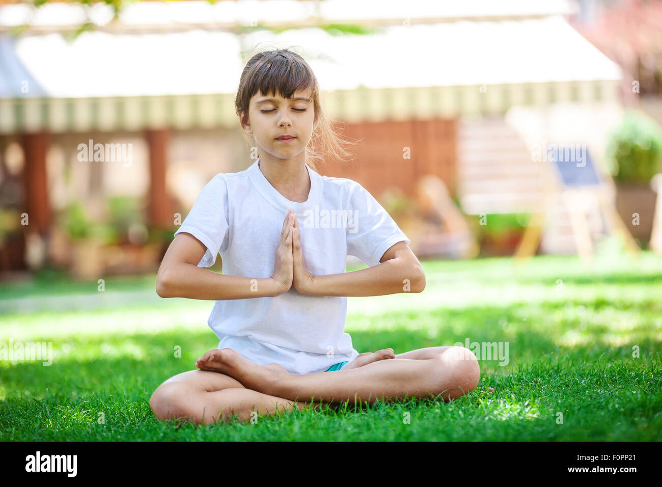 Petite fille méditer en position assise, dans une position du lotus sur l'herbe Banque D'Images