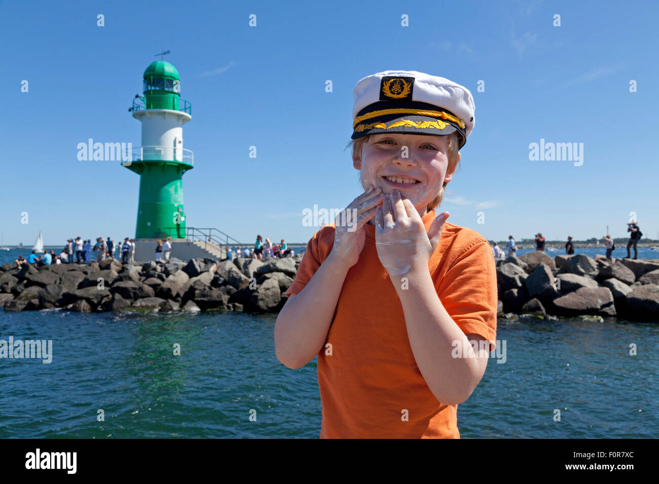 Jeune capitaine appliquez un écran solaire à son visage en face du phare, Rostock, Rostock, Mecklembourg-Poméranie occidentale, Allemagne Banque D'Images