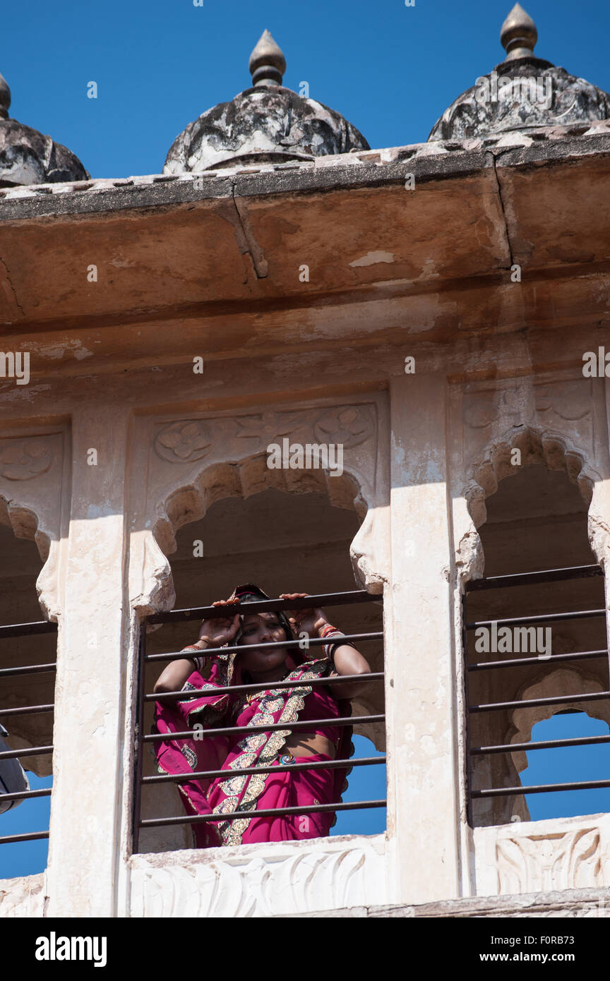 Jodhpur, Inde. La colline de grès Mehrangarh Fort du Marwar dirigeants. Une femme en sari rose du Rajasthan à travers une fenêtre. Banque D'Images