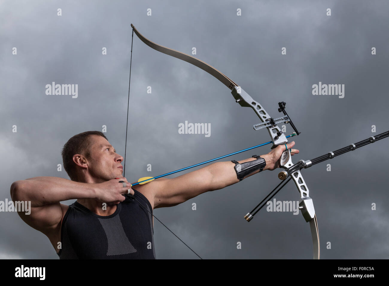 Homme dur avec arc et flèches, Close up avec ciel nuageux à l'arrière-plan. Banque D'Images