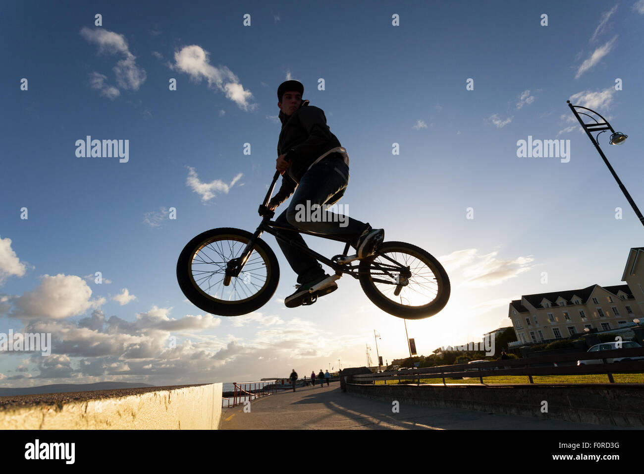 Jeune homme effectue des cascades de BMX pendant le coucher du soleil à la rue. Banque D'Images