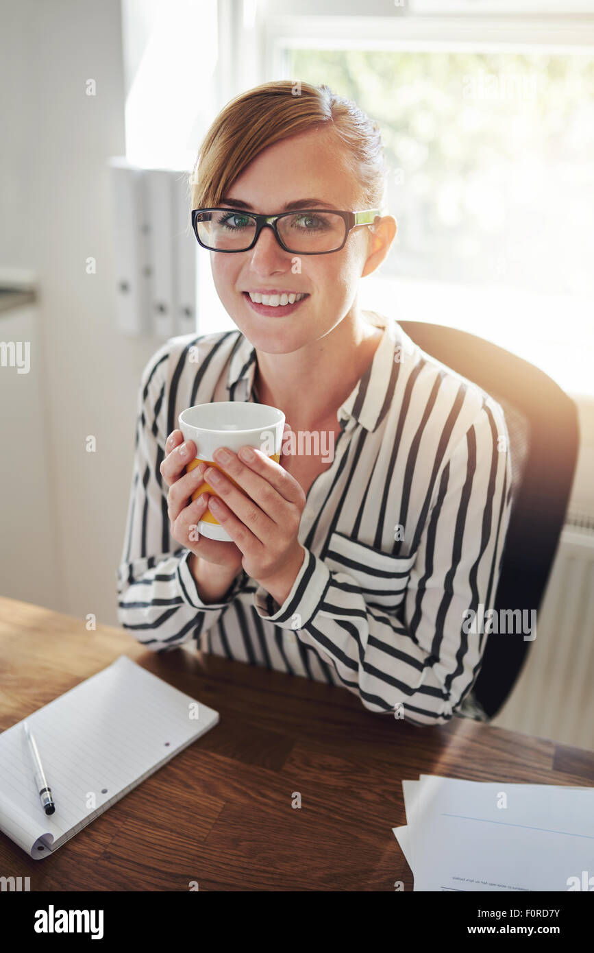 Smiling businesswoman working from home à sa nouvelle start-up web based business prenant une pause détente à boire une tasse de café chaud Banque D'Images