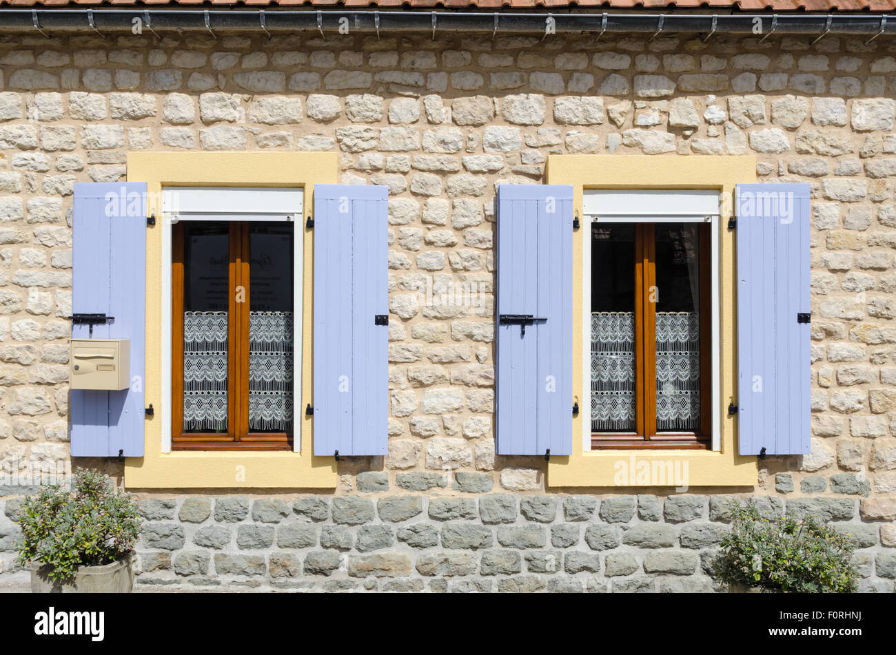 Lilac volets colorés sur les fenêtres d'une vieille maison en pierre en Normandie Française Banque D'Images