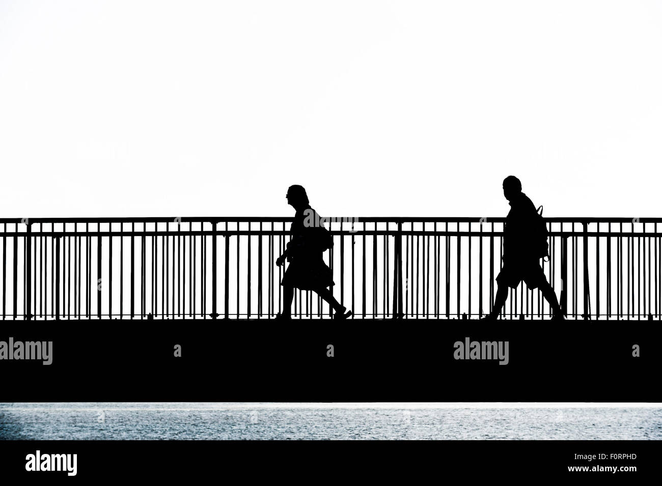 La silhouette de personnes marchant sur le pont de l'écart Louisa Broadstairs, Kent. Banque D'Images