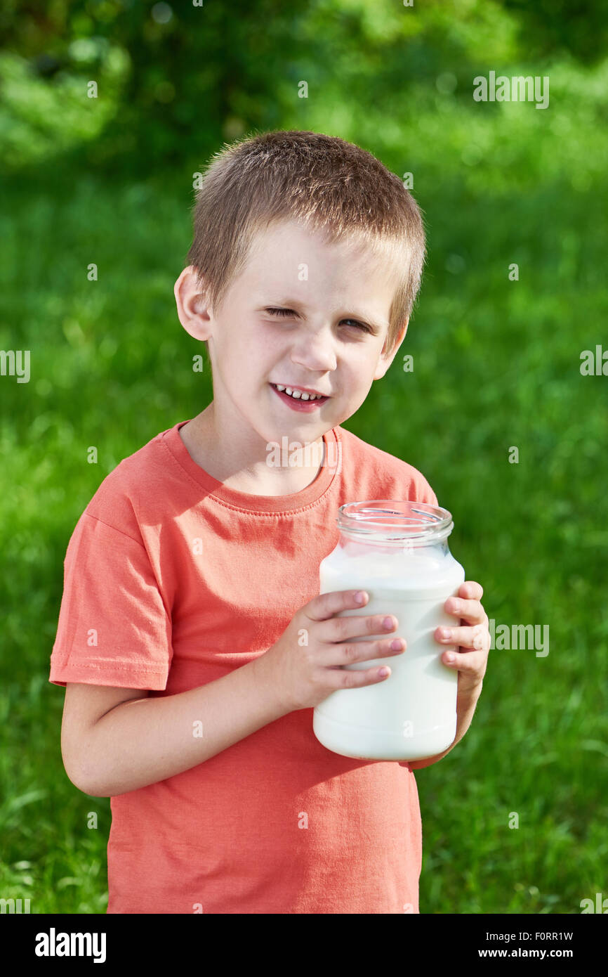 Heureux garçon avec cruche de lait dans le jardin ensoleillé Banque D'Images